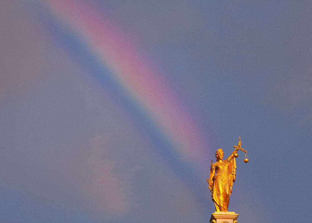 Justitia on rooftop with rainbow behind. Taken in Bruges, Belgium.